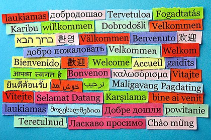 Auf der Abbildung sind viele kleine Tafeln zu sehen, auf der "Willkommen" in vielen verschiedenen europäischen und außereuropäischen Sprachen geschrieben steht.  